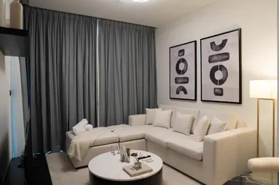 a living room with a white couch and a table at Lux Sobha Hartland 1 BR with 5 Star Resort Amenities in Dubai