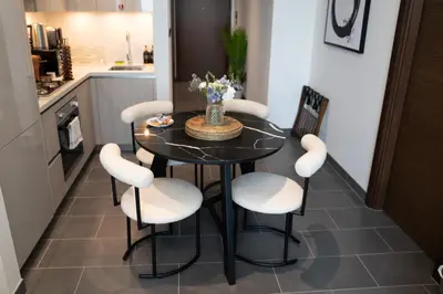 a kitchen with a black table and white chairs at Lux Sobha Hartland 1 BR with 5 Star Resort Amenities in Dubai