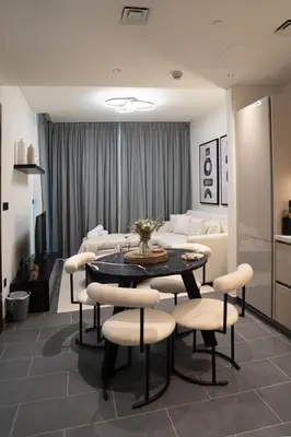 a living room with a table and chairs and a couch at Lux Sobha Hartland 1 BR with 5 Star Resort Amenities in Dubai