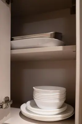 a stack of plates and bowls in a kitchen cabinet at Lux Sobha Hartland 1 BR with 5 Star Resort Amenities in Dubai