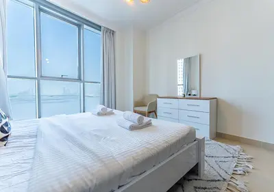 a white bedroom with a bed and a dresser and windows at Stunning 2 Bedroom at Dubai Creek in Dubai
