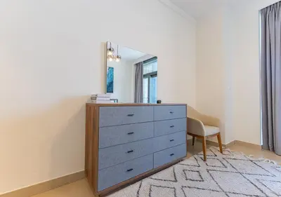 a bedroom with a dresser with a mirror and a chair at Stunning 2 Bedroom at Dubai Creek in Dubai