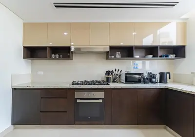 a kitchen with brown cabinets and a stove top oven at Stunning 2 Bedroom at Dubai Creek in Dubai