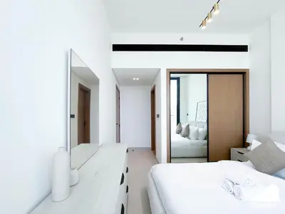 a white bedroom with two beds and a mirror at Luxury & Comfort 1B at Binghatti Amber & Balcony in Dubai