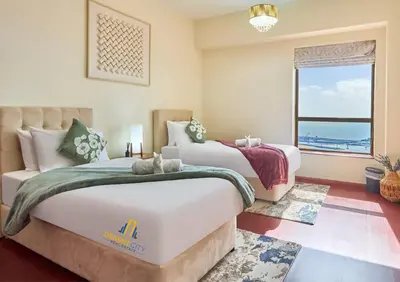 two beds in a bedroom with a view of the ocean at Beachfront 2BR, Sea & Ain Dubai View, JBR Walk Hosted by Desert City Stays in Dubai