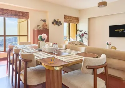 a dining room with a table and chairs and a couch at Beachfront 2BR, Sea & Ain Dubai View, JBR Walk Hosted by Desert City Stays in Dubai