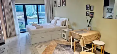 a bedroom with a bed and a table and a window at Higuests - Close to METRO Charming Studio with Lake Views in Dubai