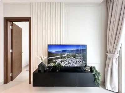a living room with a tv on a wall at 2BR Creekfront in Shobha Hartland Modern & Bright in Dubai