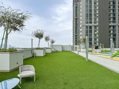 an apartment patio with grass and a playground at 2BR Creekfront in Shobha Hartland Modern & Bright in Dubai