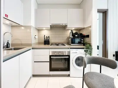 a kitchen with white cabinets and a dishwasher at 2BR Creekfront in Shobha Hartland Modern & Bright in Dubai