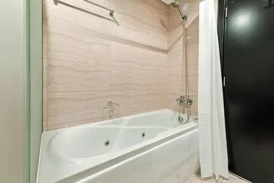 a white bath tub in a bathroom with wooden walls at 1BR at Ocean Heights Next to Tram Station in Dubai