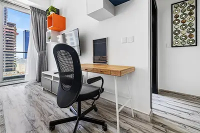 a desk with a chair in a room with a window at 1BR at Ocean Heights Next to Tram Station in Dubai