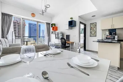 a kitchen and living room with a table with wine glasses at 1BR at Ocean Heights Next to Tram Station in Dubai