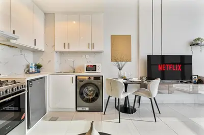 a kitchen with a washing machine and a table with chairs at Modern Studio - near Dubai Hills Mall - Pool & Gym in Dubai