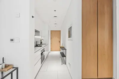 a kitchen with white walls and a wooden door at Modern Studio in Business Bay, Stylish & Central in Dubai