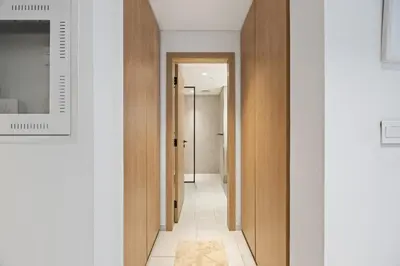 a hallway with white walls and wooden doors at Modern Studio in Business Bay, Stylish & Central in Dubai