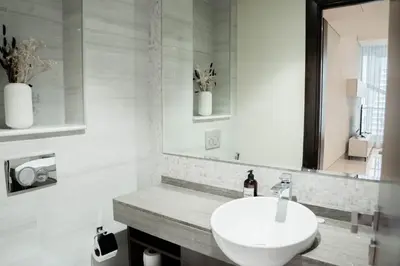 a white bathroom with a sink and a mirror at Stylish 1BR with Stunning Canal Views in Business Bay in Dubai