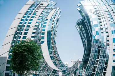 a tall glass building with a tree in front of it at Stylish 1BR with Stunning Canal Views in Business Bay in Dubai