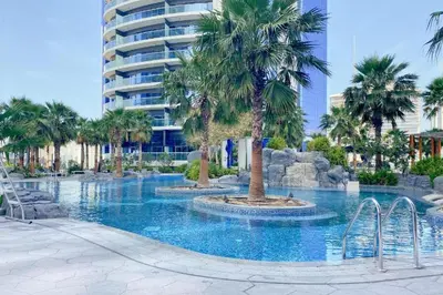 a swimming pool with palm trees and a building at PARAMOUNT TOWER B BUSINESS Bay Lux 1 bedroom Apt in Dubai