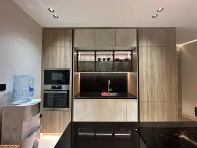 a kitchen with wooden cabinets with a sink and a microwave at Cozy Apartment Dubai Silicon Arch in Dubai