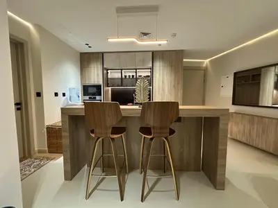 a kitchen with two bar stools at a kitchen counter at Cozy Apartment Dubai Silicon Arch in Dubai