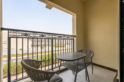 a balcony with a table and chairs and a window at Bookable- Studio Resortz By Danube with Balcony in Dubai