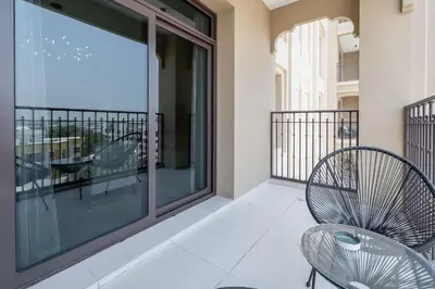 a balcony with a chair and a large window at StayShort - MJL Apartment for 2 people near Water Parks in Dubai