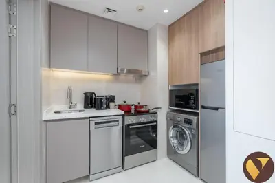 a small kitchen with a sink and a dishwasher at Vogue Marina JW Marriott with Direct Access to Marina Mall, Studio Apartment with Balcony and Marina Skyline View, Access to all Amenities in Dubai