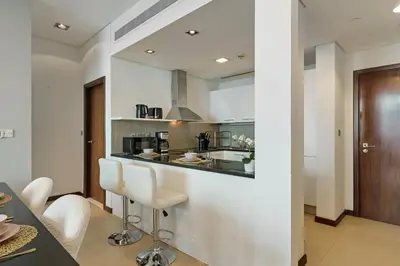 a kitchen with white walls and a counter and chairs at Gorgeous 2BR in DIFC close to Metro & Dubai Mall in Dubai