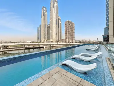 a swimming pool with white lounge chairs in a city at BLVD - Stylish Missoni Stay - Canal View in Dubai