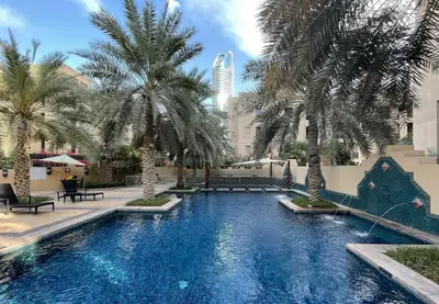 a swimming pool with palm trees in a courtyard at Dubai 2BR Pool View, Near Burj Khalifa, Canal & Attractions in Dubai