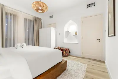 a white bedroom with a bed and a refrigerator at Dubai 2BR Pool View, Near Burj Khalifa, Canal & Attractions in Dubai