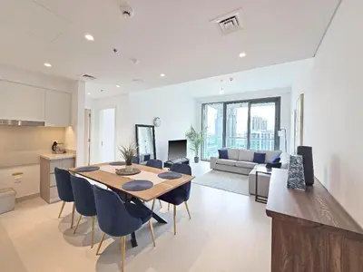 a kitchen and living room with a table and chairs at Deluxe 1-Bedroom in The Grand - Waterfront and Skyline Views in Dubai