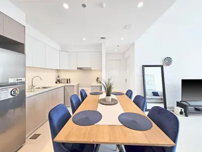 a kitchen with a wooden table and blue chairs at Deluxe 1-Bedroom in The Grand - Waterfront and Skyline Views in Dubai