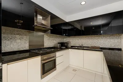 a kitchen with white cabinets and black appliances at Elegant 2BR APT, 3 minutes to Burj Khalifa in Dubai
