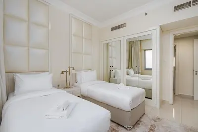 a white bedroom with two beds and a mirror at Elegant 2BR APT, 3 minutes to Burj Khalifa in Dubai