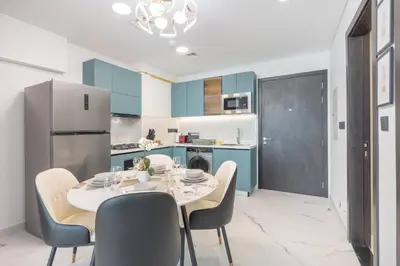a kitchen with a table and chairs and a refrigerator at StayShort - Al Barsha Apartment Sleeps 2 with Private Balcony in Dubai