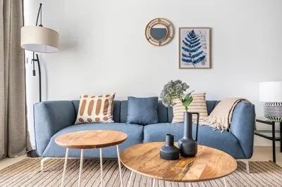 a blue couch in a living room with a table at Water View I Chic 1BR I Mayfair I 3 Sleeps I Fast Wi-Fi I Walkable Area in Dubai