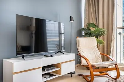 a living room with a tv and a chair at Water View I Chic 1BR I Mayfair I 3 Sleeps I Fast Wi-Fi I Walkable Area in Dubai