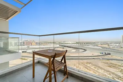 a table and a chair in front of a large window at Luxury Studio with Gym, Pool & Badminton Court in Dubai