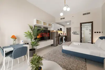 a living room with a bed and a dining room at Luxury Studio with Gym, Pool & Badminton Court in Dubai