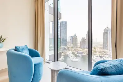 a living room with two blue chairs and a large window at Incredibly Elegant 1BDR with full Marina Views in Dubai