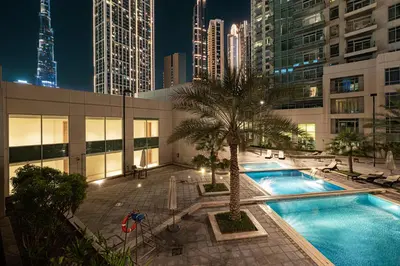 a swimming pool with a palm tree on a building at Cozy Studio Near Burj Khalifa Sleeps 3 in Dubai