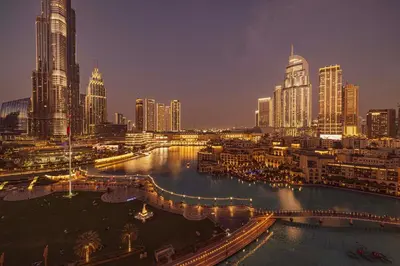 a city skyline at night with a river and buildings at Stunning 2BR with Panoramic Burj & Fountain view in Dubai