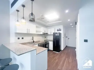 a kitchen with white cabinets and a black refrigerator at Urban Duplex Hideaway l Gym, Pool & Balcony in Dubai