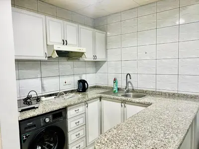a kitchen with white cabinets and a dishwasher at Sleep 6 Mina Road in Dubai