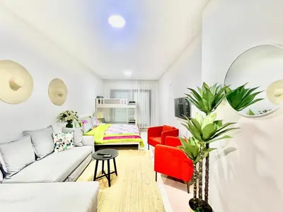 a living room with a white couch and red chairs at Sleep 6 Mina Road in Dubai