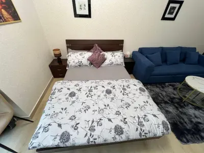 a bedroom with a bed and a blue couch at Cozy Studio with Sofa bed beside DMCC Metro & Dubai Marina in Dubai