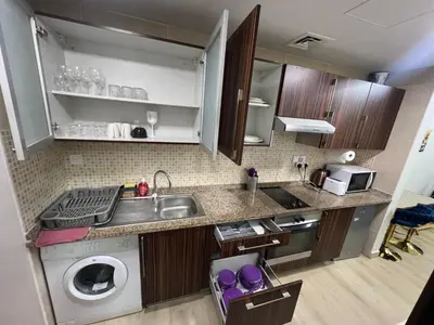 a kitchen with a sink and a washing machine at Cozy Studio with Sofa bed beside DMCC Metro & Dubai Marina in Dubai