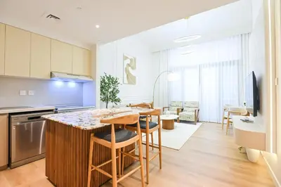 a kitchen and living room with a table and chairs at GV Holiday Homes DXB - Cozy 2BR Apartment in Town Square Dubai in Dubai
